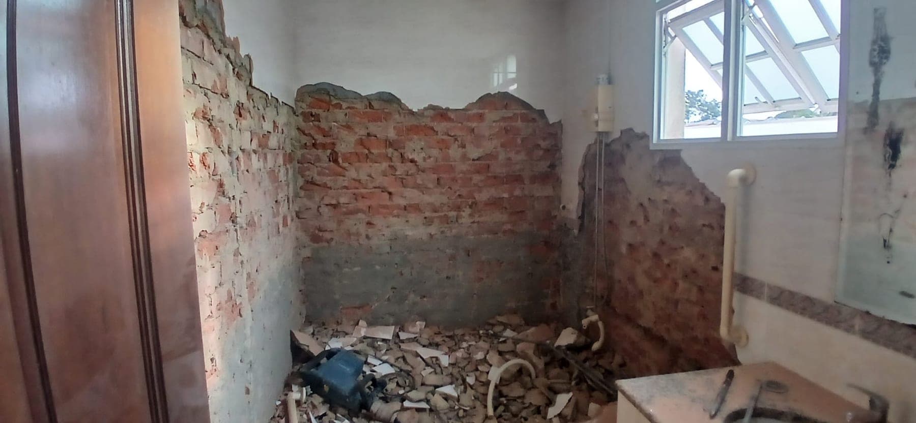 Wet area with exposed brick walls, debris and breaker tool during demo works